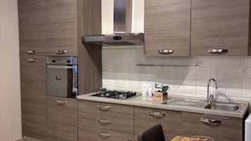 A modern kitchen with wooden cabinets, a gas stove, a built-in oven, and a dining area with a wooden table and chairs.