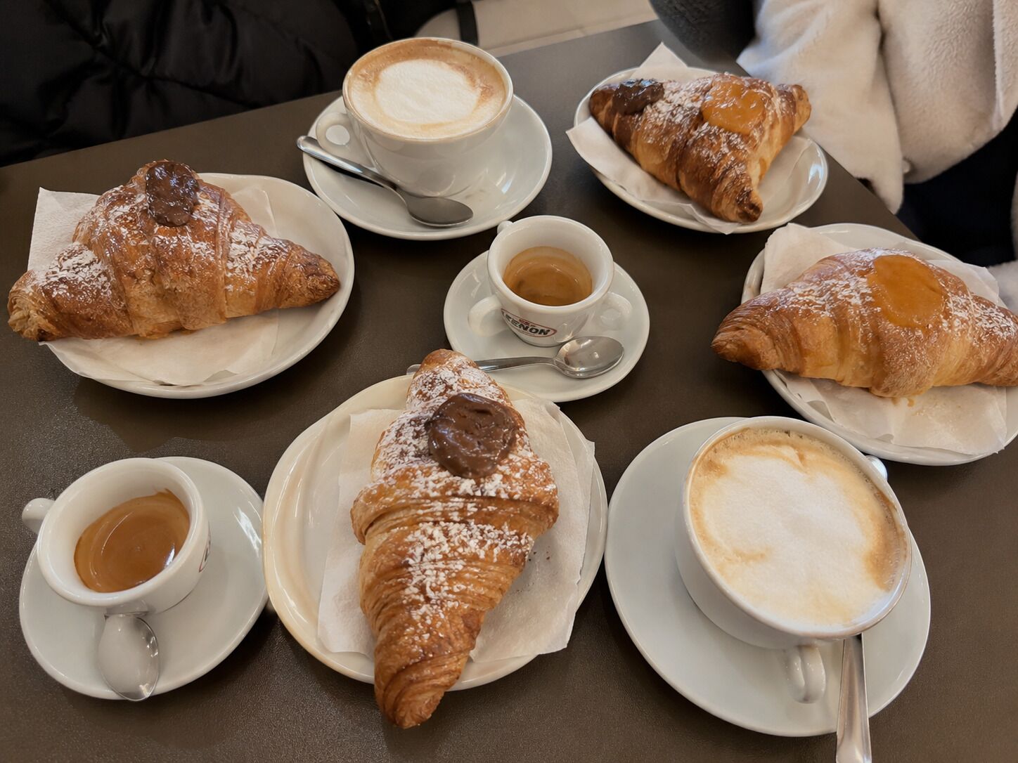 A table with croissants and cups of coffee.
