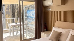 A hotel room with a bed, a small table, a chair, and a balcony with a view. - IL PALAZZETTO GAETA (Gaeta)