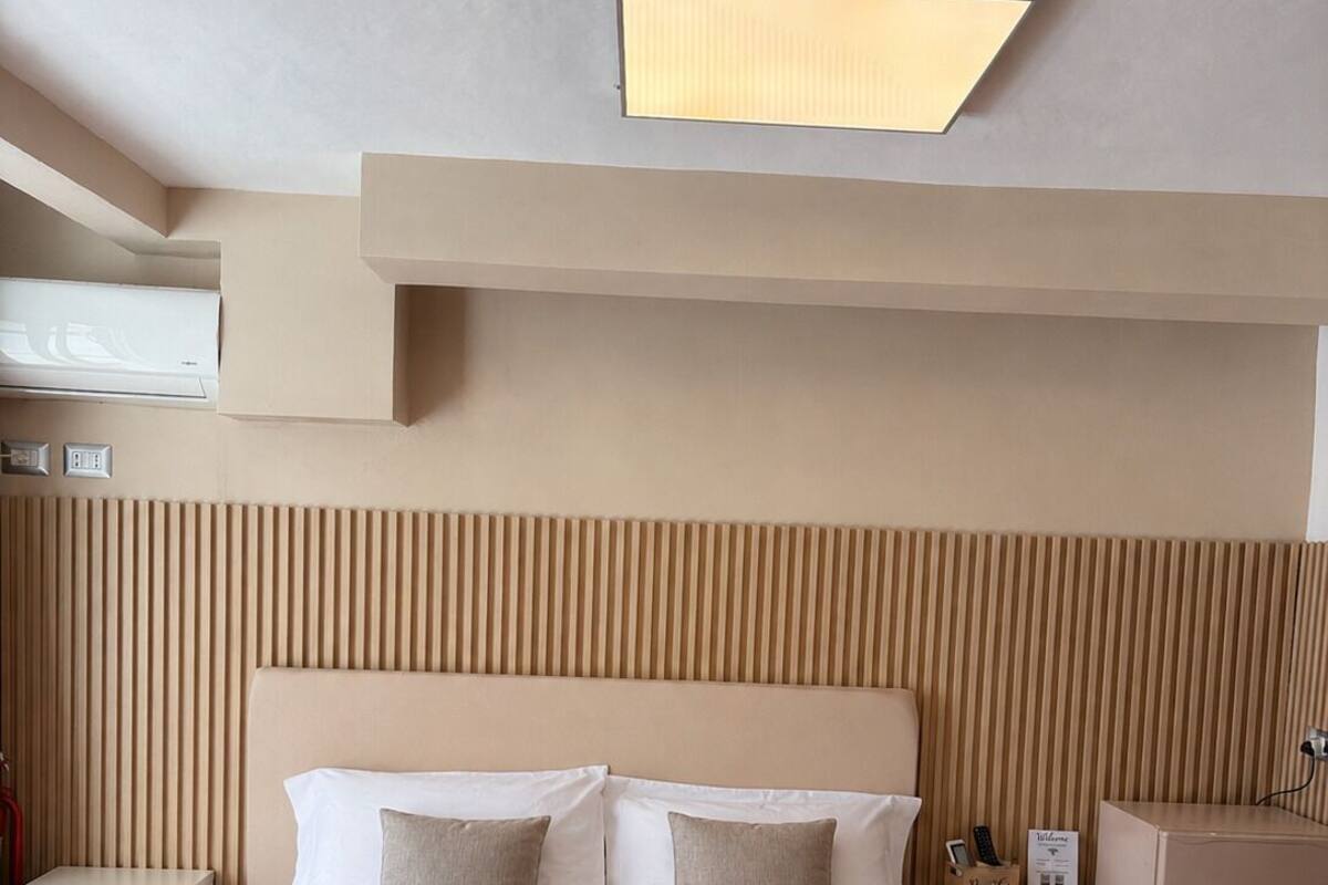 Ein Hotelzimmer mit einem großen Bett, Nachttischen, einem Kleiderschrank und einer Deckenleuchte.