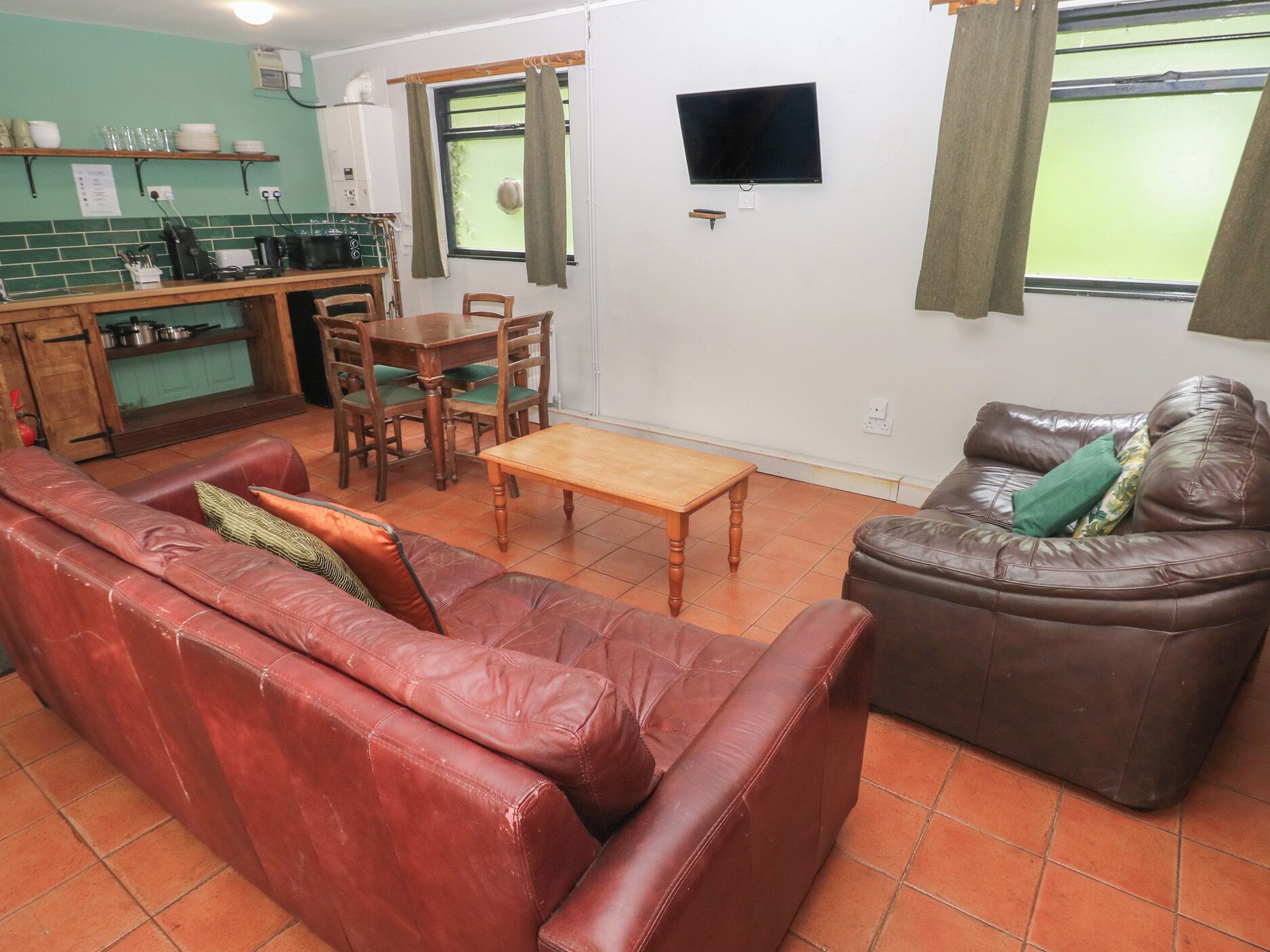 Ein Wohnzimmer mit einem roten Ledersofa, einem braunen Leder-Sofa, einem Holztisch und einem Essbereich mit einem Holztisch und Stühlen.