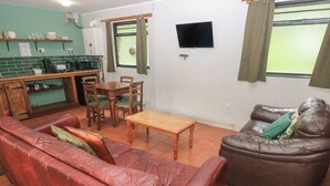 Ein Wohnzimmer mit einem roten Ledersofa, einem braunen Leder-Sofa, einem Holztisch und einem Essbereich mit einem Holztisch und Stühlen.