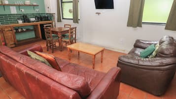 Ein Wohnzimmer mit einem roten Ledersofa, einem braunen Leder-Sofa, einem Holztisch und einem Essbereich mit einem Holztisch und Stühlen.