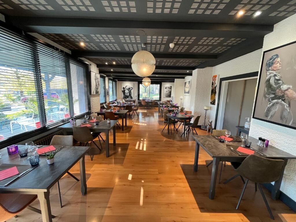 Un restaurante espacioso con techos altos, suelo de madera y decoración moderna.