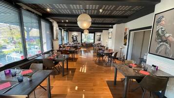 Un restaurante espacioso con techos altos, suelo de madera y decoración moderna.