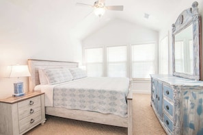 A bedroom with a bed, a nightstand, a dresser, a ceiling fan, and a window with blinds. - Haven House-Heated Pool, Spa, Views, 1 blk to sea (Kill Devil Hills)