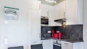 Eine moderne Küche mit weißen Schränken, einer schwarzen Arbeitsplatte und roten Geräten.