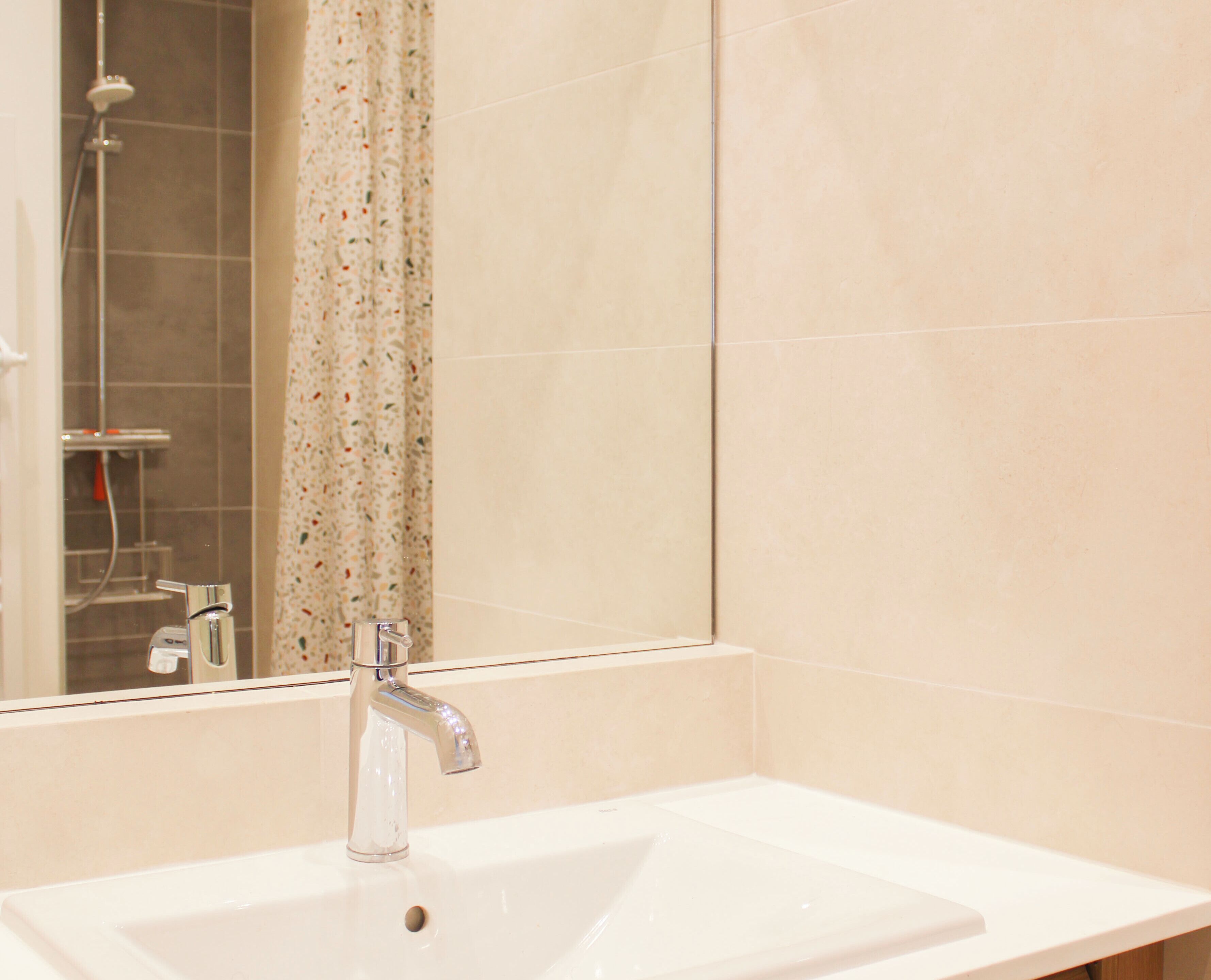 Un baño con un lavamanos blanco, un espejo y una ducha.