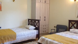 Un dormitorio con dos camas, un armario y una silla.