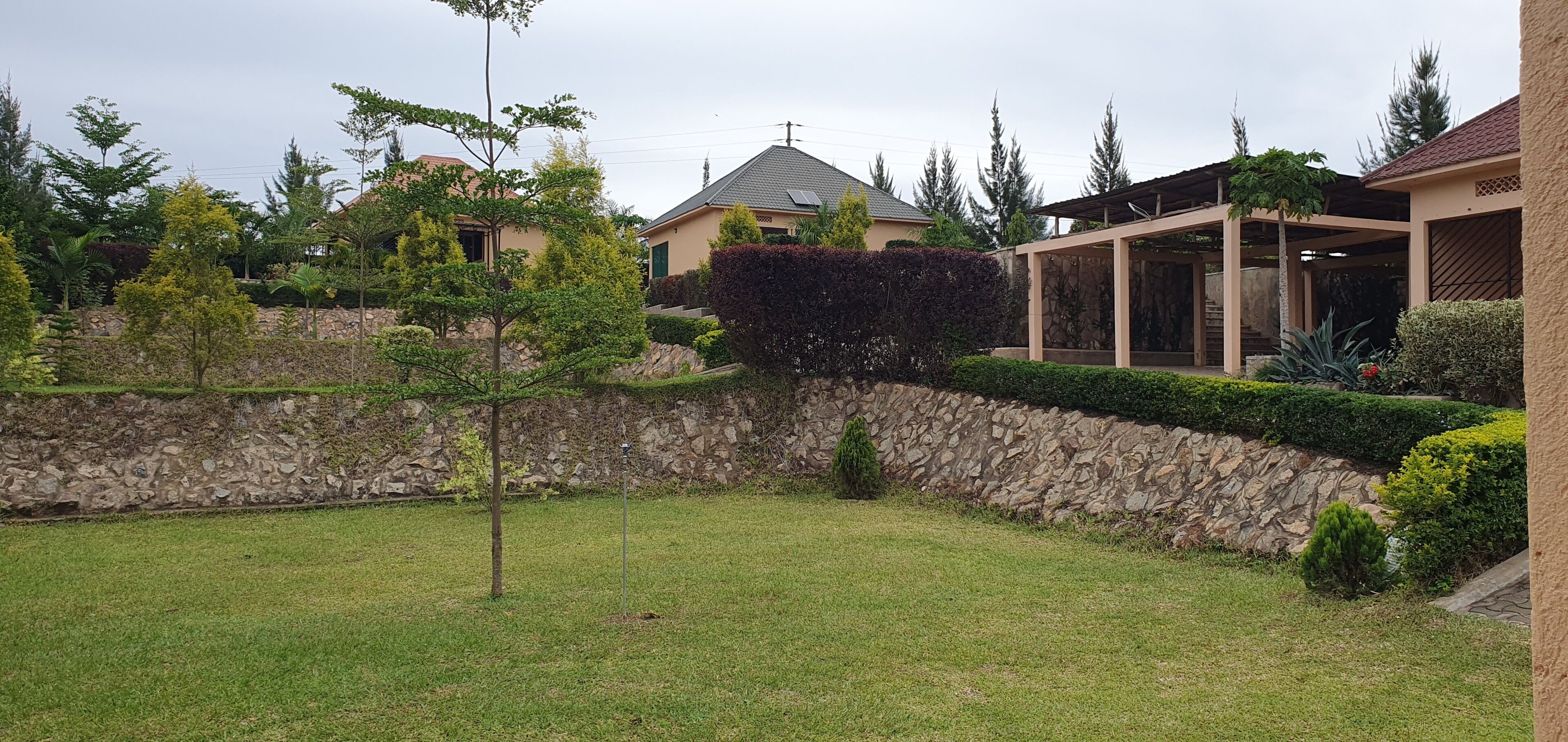 Zona residencial con muro de piedra, césped y casas de diversos estilos arquitectónicos.