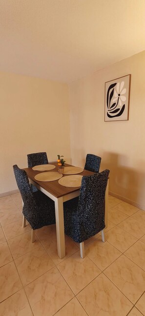 A dining area with a round table, four chairs, and a wall-mounted artwork. - Large apartment with a 35 m² terrace (Saint-Raphaël)