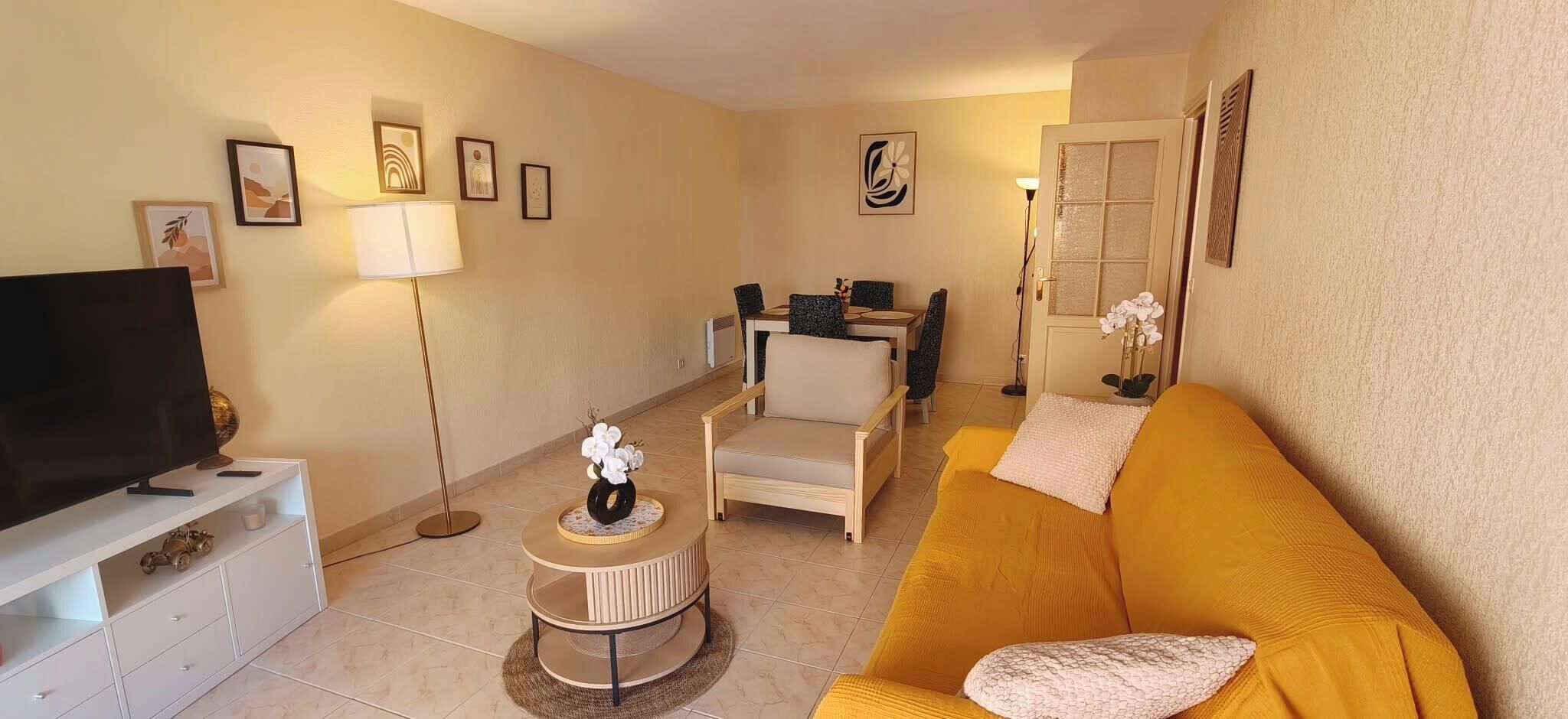 A living room with a TV, sofa, chairs, and a dining table.