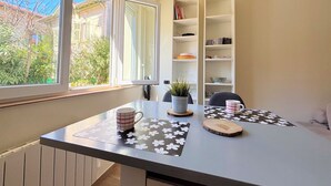 Une pièce avec une fenêtre, une table avec un set de table, une plante en pot et une bibliothèque.