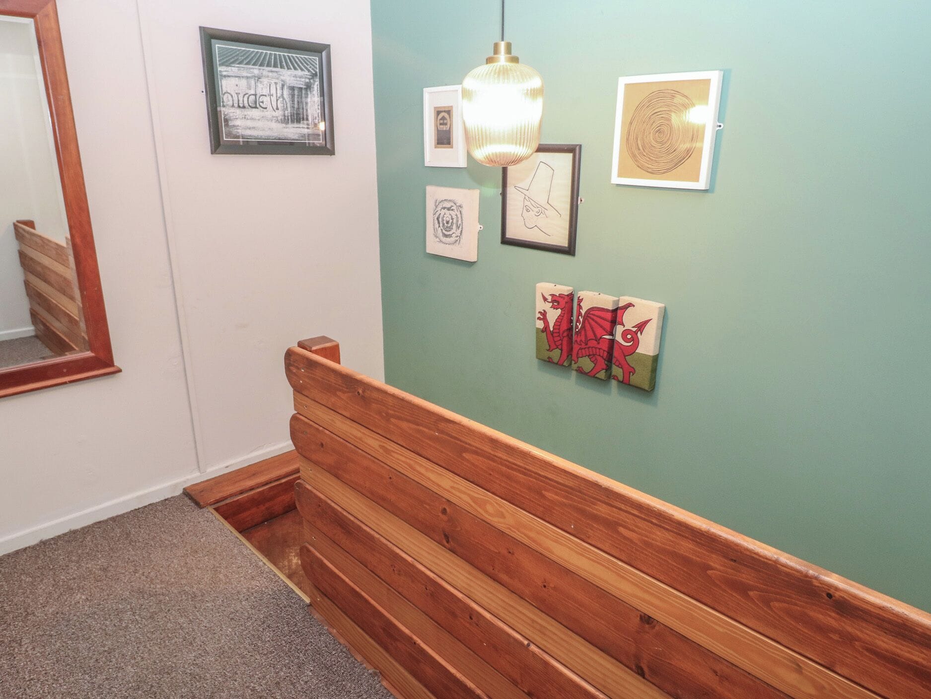 Ein Flur mit einer Holzbank, einem Spiegel und Kunstwerken an der Wand.