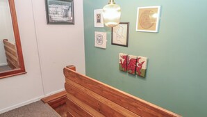 Un pasillo con un banco de madera, un espejo y obras de arte en la pared.
