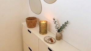 A white console with three mirrors, a candle, a basket, a vase with a plant, and a plate with keys. - Beautiful 45 m² apartment with terrace in Nice (Nice)