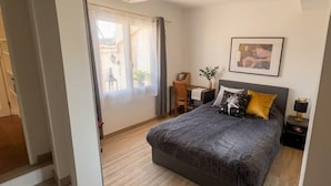 A modern bedroom with a large bed, a desk, and a chair, a window with curtains, and a framed picture on the wall. - Beautiful 45 m² apartment with terrace in Nice (Nice)