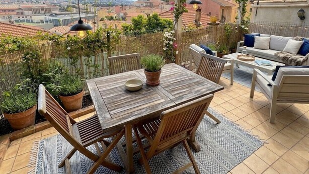 A patio with a wooden table and chairs, a sofa, and potted plants. - Beautiful 45 m² apartment with terrace in Nice (Nice)
