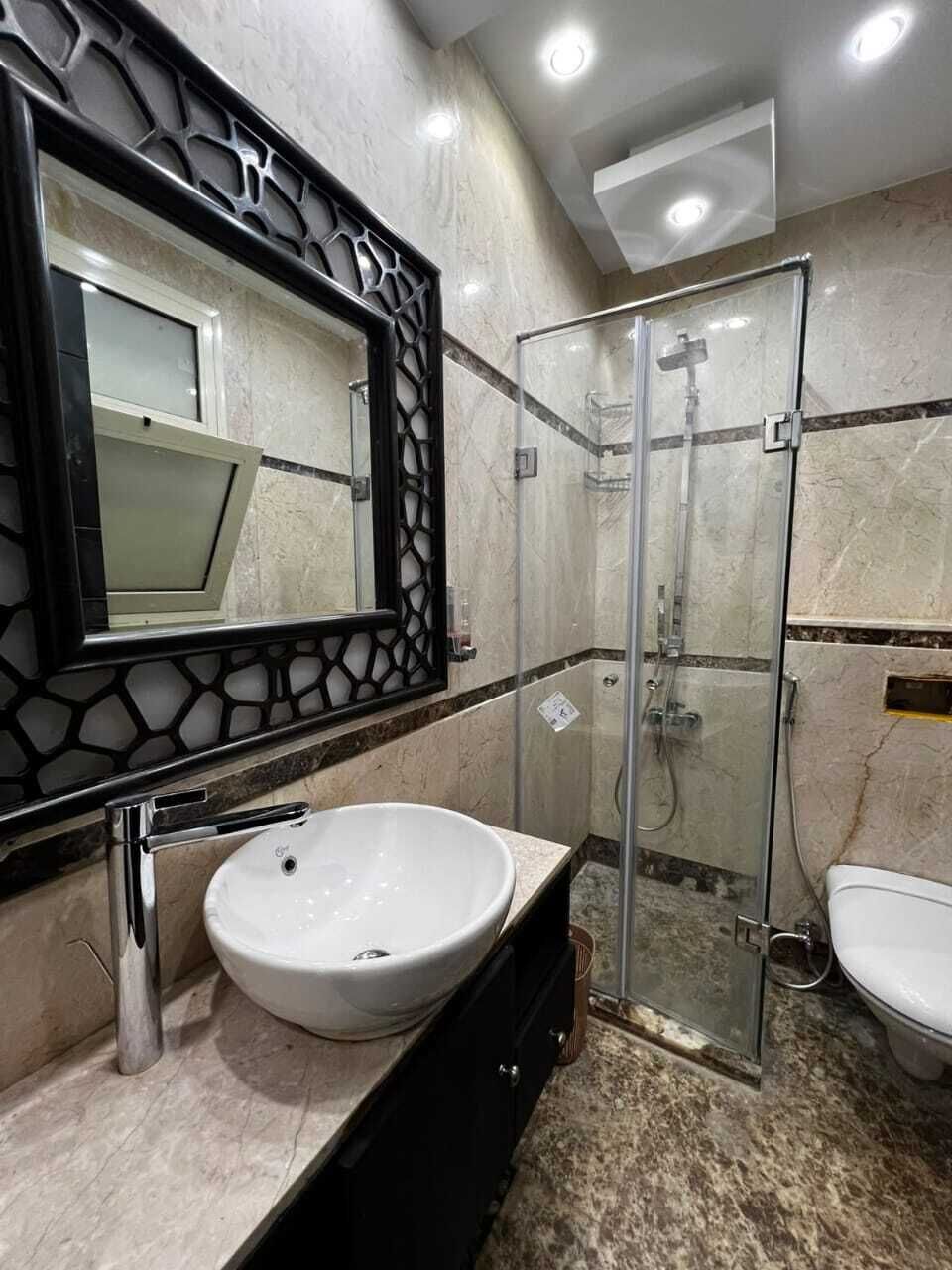 Ein Badezimmer mit einem weißen Waschbecken, einer Duschkabine und einer Toilette.