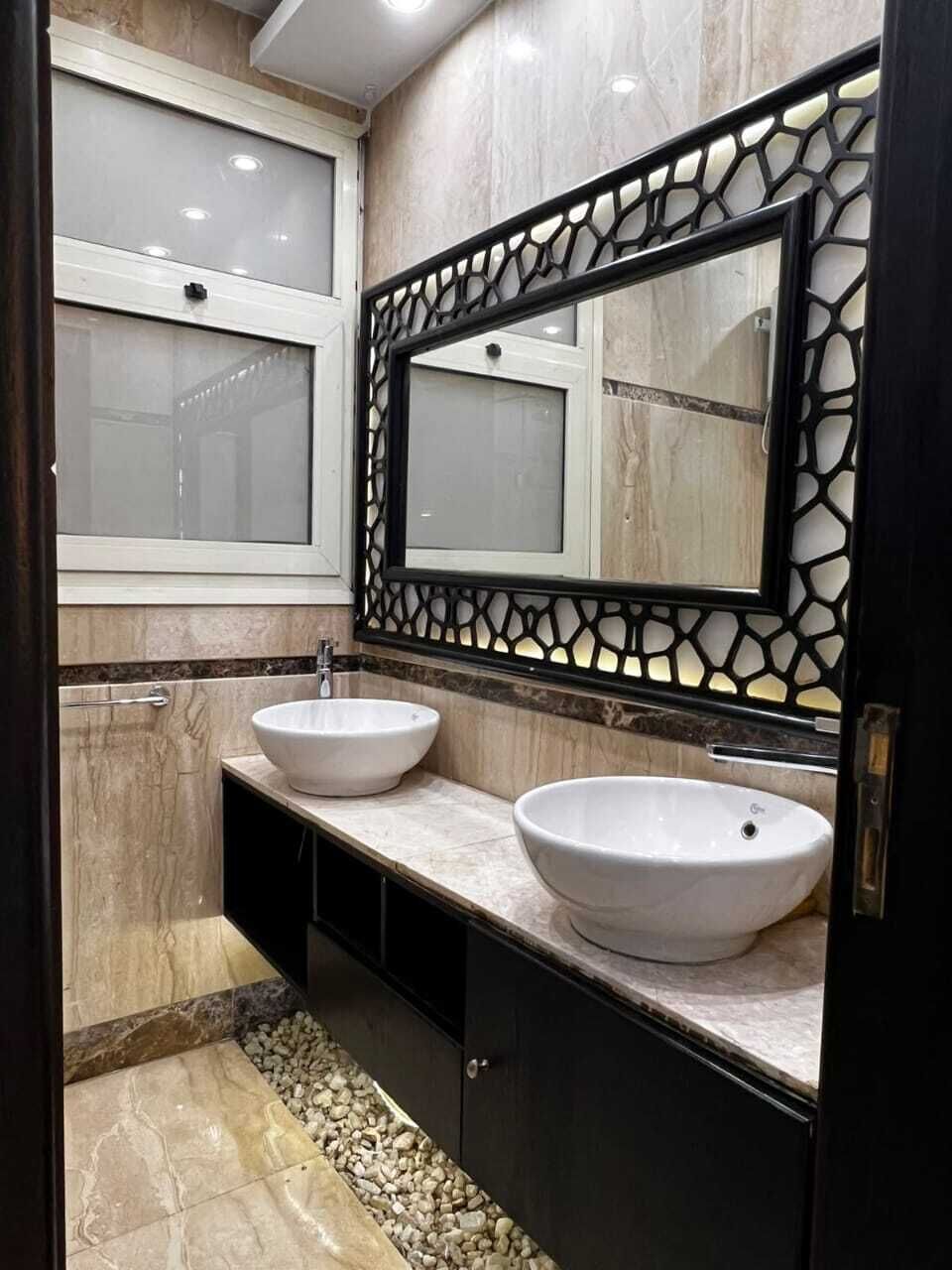 A bathroom with two sinks, a mirror with a decorative frame, and a window.