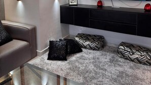 A modern living room with a flat-screen TV, a sofa, a glass coffee table, and a decorative wall panel. - ELITE New Modern 3BR Apartment (New Cairo)
