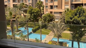 A residential building with a pool, surrounded by greenery and palm trees. - ELITE New Modern 3BR Apartment (New Cairo)