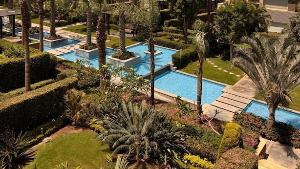 A modern building with multiple balconies, a swimming pool, and lush greenery. - ELITE New Modern 3BR Apartment (New Cairo)