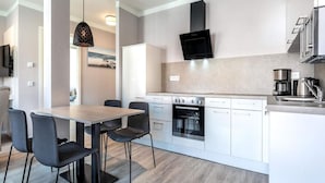 A modern kitchen with a dining area, built-in oven, and a flat-screen TV. - 4 Star Holiday Home in Travemunde (Lübeck)