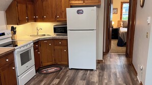 Una cocina con armarios de madera, un refrigerador blanco y un microondas.