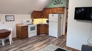 Una cocina con gabinetes de madera, un refrigerador blanco, una estufa y un microondas.