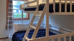 Habitación con literas, ventana, cortinas y radiador.