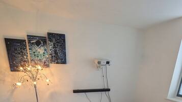 Una camera da letto moderna con un letto, un comodino e un proiettore montato a parete.