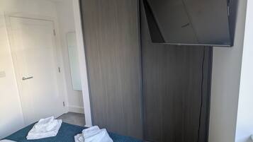 Een hotelkamer met een bed, een flatscreen televisie aan de muur, een kledingkast en een deur.