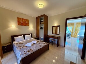 A hotel room with a bed, a desk, a mirror, and a view of the outdoors. - Thomas apartments Corfu (Corfu)