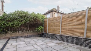 A paved patio with a wooden fence and a brick wall.