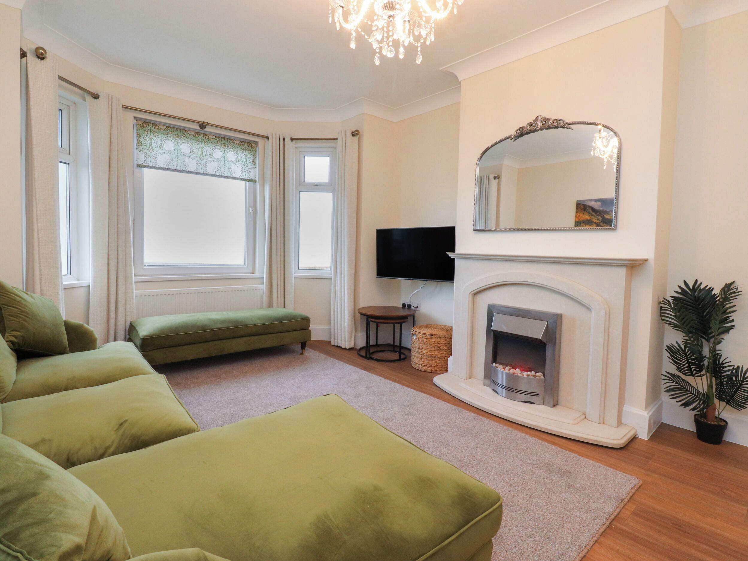 Una sala de estar con chimenea, sofá verde y televisor.