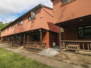 A row of log cabin-style buildings with wooden balconies and a gravel driveway. - Cabin No. 12 - Salt and Fern Cabins (Port Talbot)