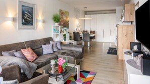 A modern living room with a sofa, coffee table, and a flat-screen TV. - Apartment 'Lubeca' with Loggia (Goslar)