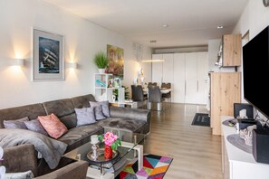 A modern living room with a sofa, coffee table, and a flat-screen TV. - Apartment 'Lubeca' with Loggia (Goslar)