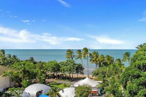A coastal view with palm trees, a beach, and a dome-shaped building. - Amalfi—Ocean Views & Pool near Beach & Restaurants (Trinity Beach)
