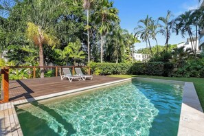 A swimming pool with clear water, surrounded by lush greenery and palm trees. - Amalfi—Ocean Views & Pool near Beach & Restaurants (Trinity Beach)