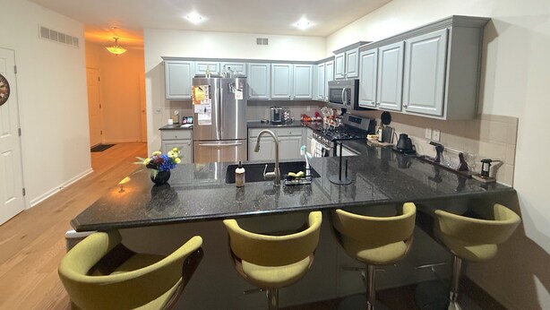 A modern kitchen with a central island, bar stools, stainless steel appliances, and light gray cabinets. - Azura Amphitheater Home — Sleeps 6 (Kansas City)