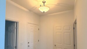 A hallway with white doors, a wooden floor, and a ceiling light fixture. - Azura Amphitheater Home — Sleeps 6 (Kansas City)