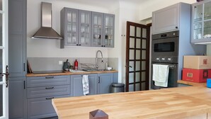 Una cocina con gabinetes grises, una encimera de madera, un horno de acero inoxidable y un salpicadero de azulejos.