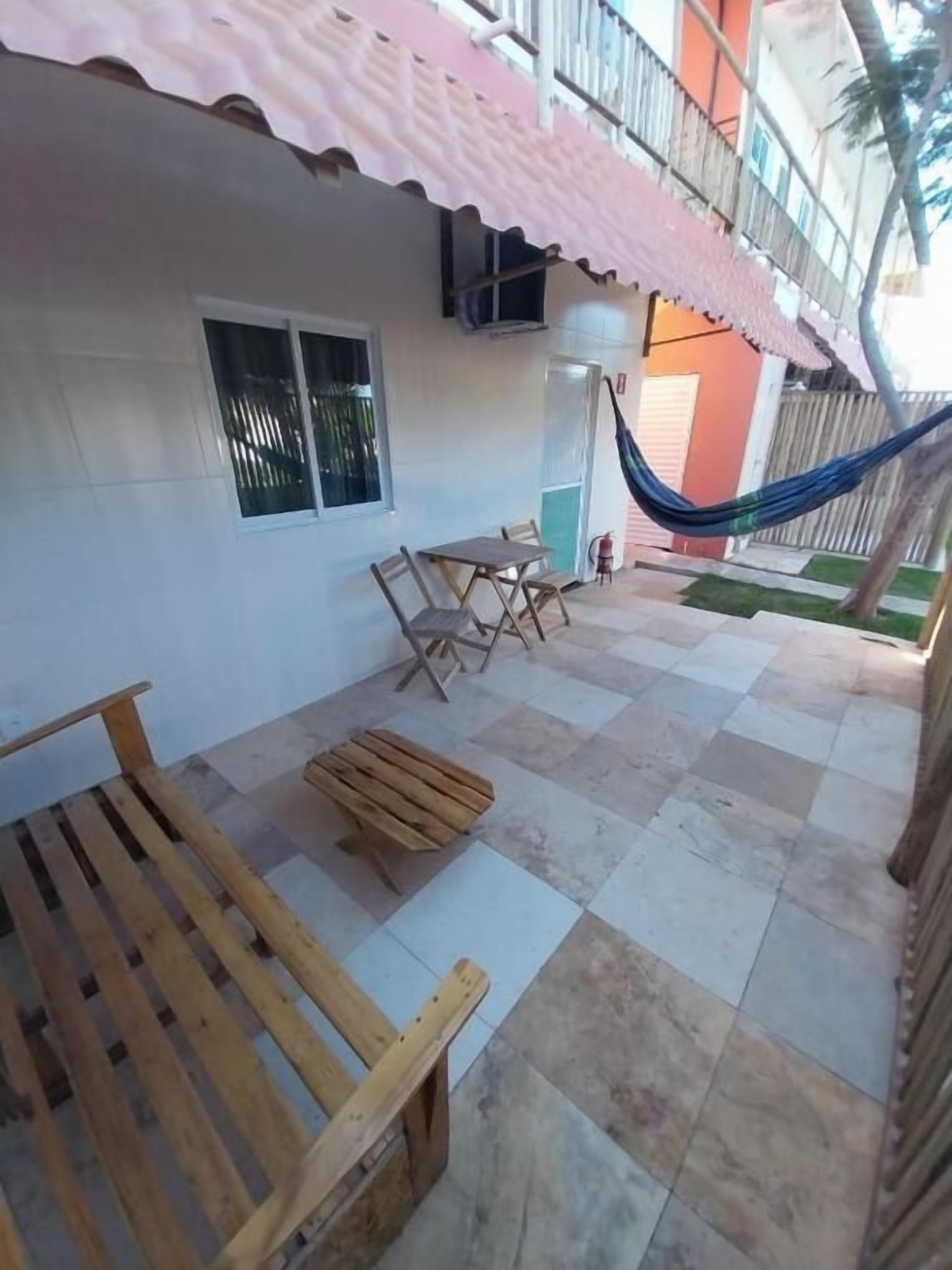 Une terrasse avec un hamac, des meubles en bois et un sol carrelé.