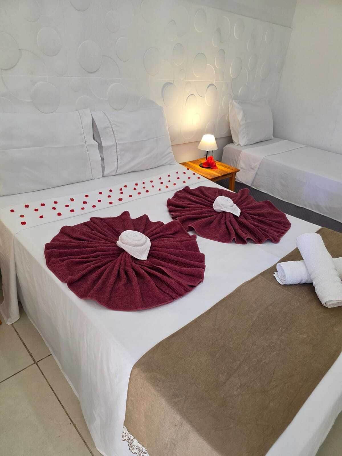 A hotel room with a bed, pillows, a nightstand with a lamp, and a sofa.