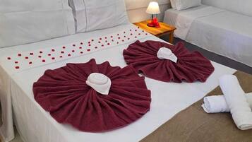 A hotel room with a bed, pillows, a nightstand with a lamp, and a sofa.