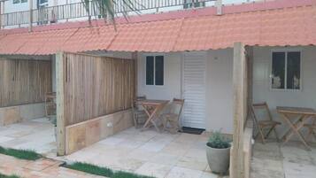 Un patio con suelo de baldosas, mobiliario de madera y una planta en maceta.