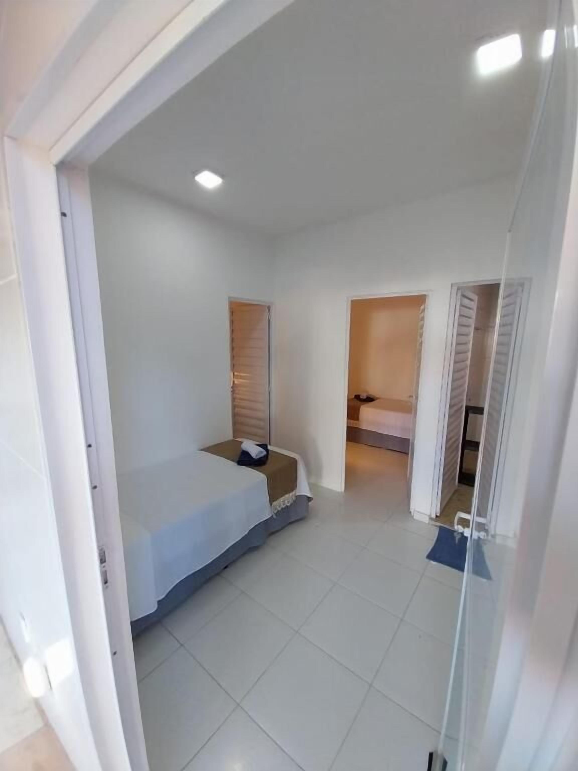 Une chambre à coucher avec un lit, une petite table et une porte donnant sur une autre pièce.