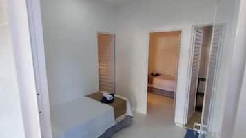 Un dormitorio con una cama, una mesita y una puerta que da a otra habitación.